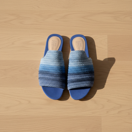 Pair of blue striped handmade slippers on a wooden surface