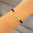 Gold Lebanon bracelet with black cord on a wrist against a neutral background