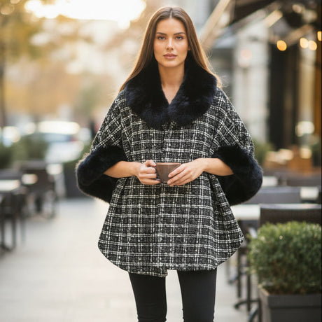 Woman wearing a black and white checkered puncho with a fur collar on a city street