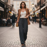 Woman walking on a city street wearing a brown blazer and dark pants.