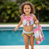 Child in a unicorn-themed swimsuit holding a matching bag by a pool.