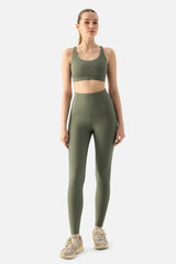 Woman wearing a green sports bra and leggings on a white background
