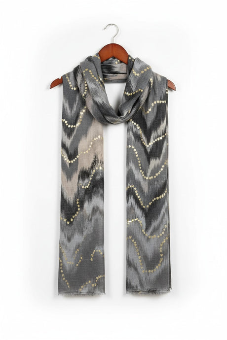 Grey scarf with gold patterns on a wooden hanger against a white background