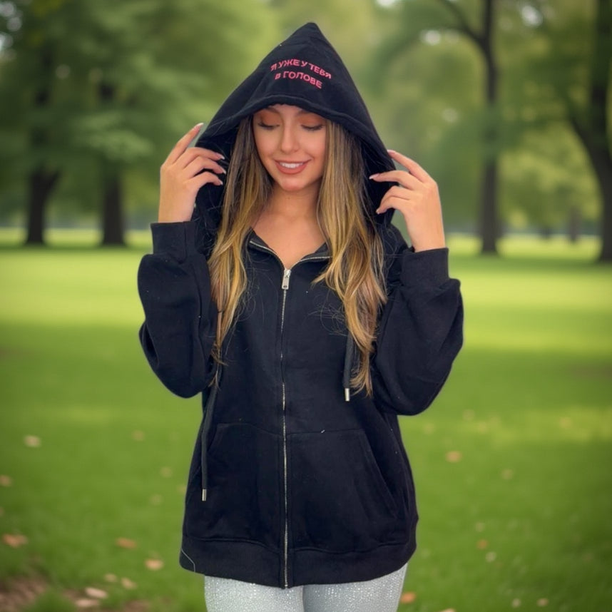 Woman wearing a black jacket with text in a park