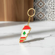 Gold tone keychain charm shaped like the map of Lebanon, enamelled as the flag