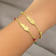 Gold bracelet with red, green, and gold beads and Lebanon's map on a wrist against a neutral background