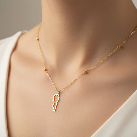 Gold necklace with a delicate lebanon map pendant on a neutral background