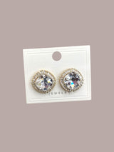Pair of pearl earrings on a jewelry display card against a beige background
