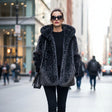 Woman wearing a black fur coat with leopard print design on a city street