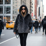 Woman in a black fur coat with leopard print design walking on a city street