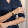 Person wearing a gold leopard silk cuff bracelet on a navy blue dress against a neutral background