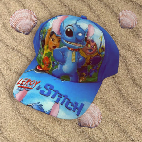 Blue kids cap laid on sand showing cartoon alien characters and large text across the peak
