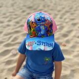 Child seen from the front in a pink and blue cap printed with blue alien cartoon characters
