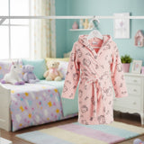 Pink children's robe with cartoon Hello Kitty patterns hanging in a room with colorful bedding and toys