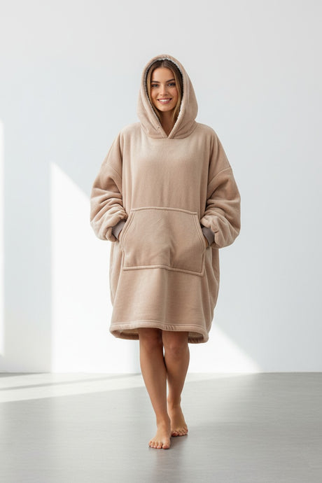Person wearing a beige hooded garment in a minimalistic setting