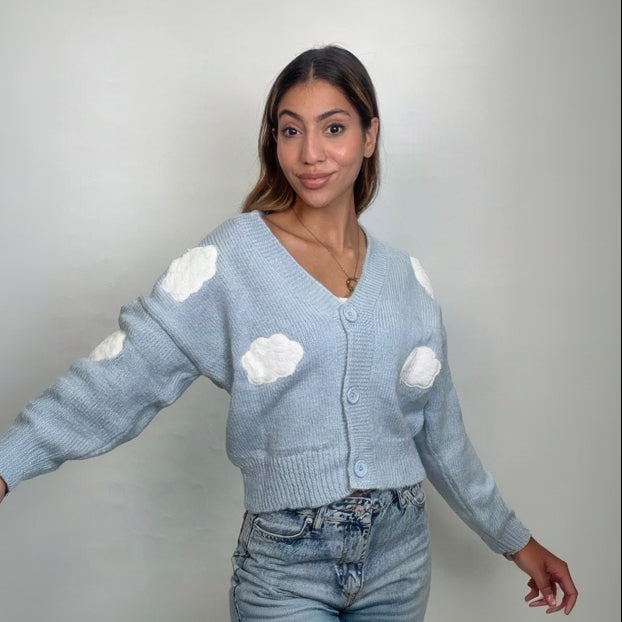 Light blue knit cardigan with fluffy white cloud appliques, arm outstretched