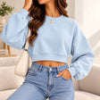 Woman in a light blue cropped crew neck sweatshirt with a wide ribbed waistband and jeans