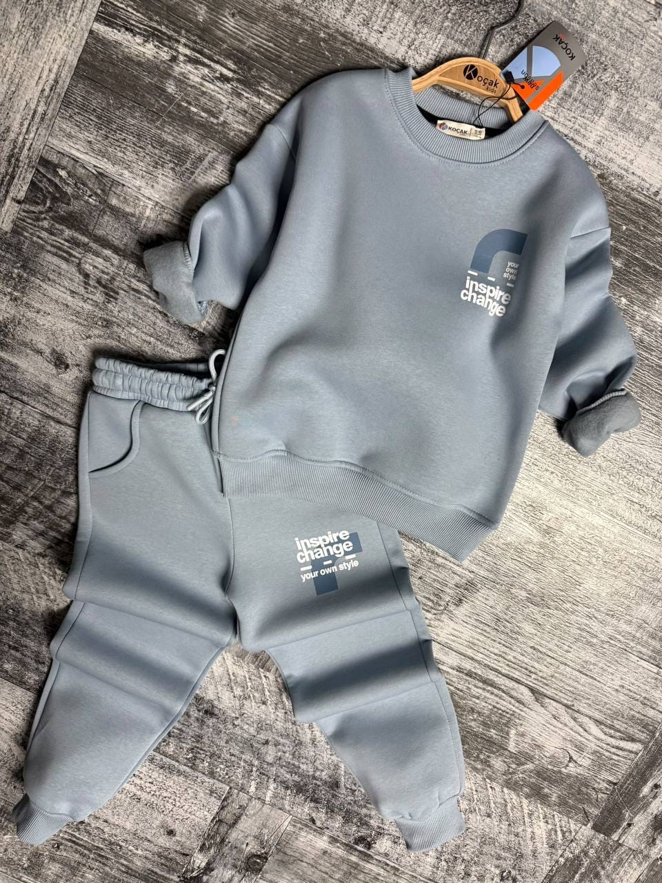Light blue sweatshirt and cuffed joggers laid flat on a wooden floor