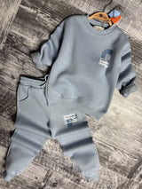 Light blue sweatshirt and cuffed joggers laid flat on a wooden floor
