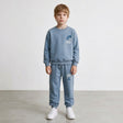 Boy in a light blue crew neck sweatshirt and drawstring joggers