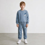 Boy in a light blue crew neck sweatshirt and drawstring joggers