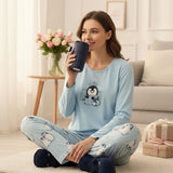 Woman in a light blue penguin print pyjama set relaxing on a couch with a mug - Jack Gifts Online Lebanon