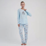 Woman wearing a light blue cotton pyjama set with penguin design on a white background