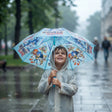 Smiling boy in a clear raincoat holding a light blue umbrella with Sonic character