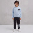 Smiling boy in a light blue street art sweatshirt and black graffiti joggers