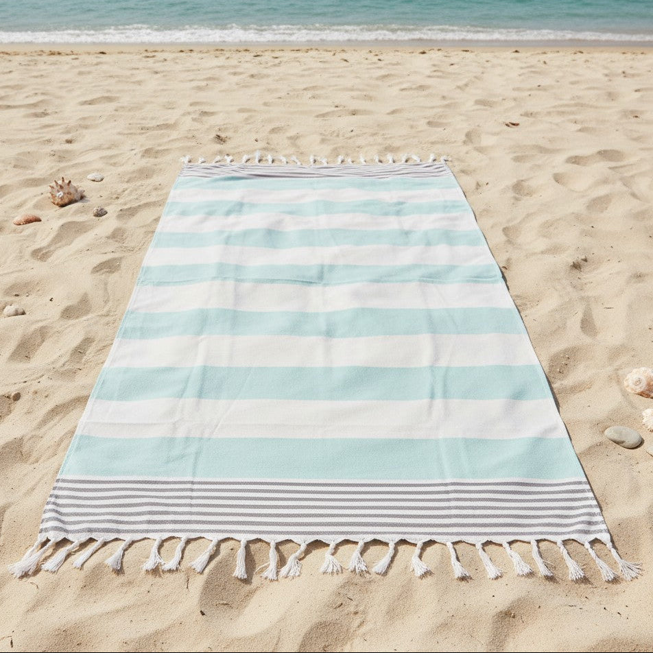 Striped beach towel on a sandy beach with ocean in the background