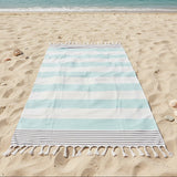 Striped beach towel on a sandy beach with ocean in the background