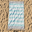 Striped beach towel on sand with dimensions indicated