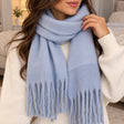 Pale blue blanket scarf wrapped twice at the neck with soft twisted tassels