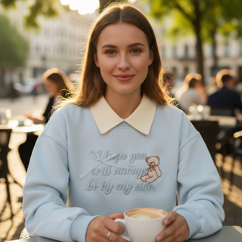 Close view of tonal teddy bear embroidery and cursive lettering on powder blue fleece