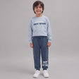 Smiling boy in a light blue Vacay Season sweatshirt and denim blue joggers