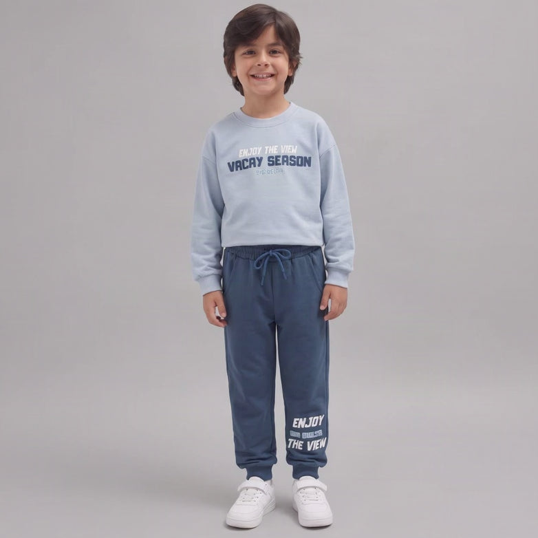 Smiling boy in a light blue Vacay Season sweatshirt and denim blue joggers
