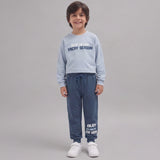 Smiling boy in a light blue Vacay Season sweatshirt and denim blue joggers