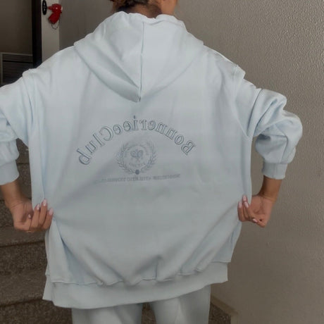 Back view of the pale blue hoodie showing the embroidered motif