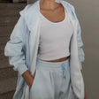 Close view of the pale blue velour hoodie worn open over a white tank