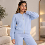 Light blue zip up knit cardigan with a silver zip and matching pants, worn standing in a bright bedroom
