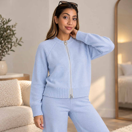 Light blue zip up knit cardigan with a silver zip and matching pants, worn standing in a bright bedroom
