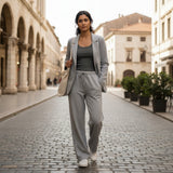 Light grey jersey blazer and drawstring joggers worn on a cobbled square with a tote bag