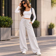 Woman in light grey wide leg sweatpants with a drawstring waist, a white crop top and white sneakers