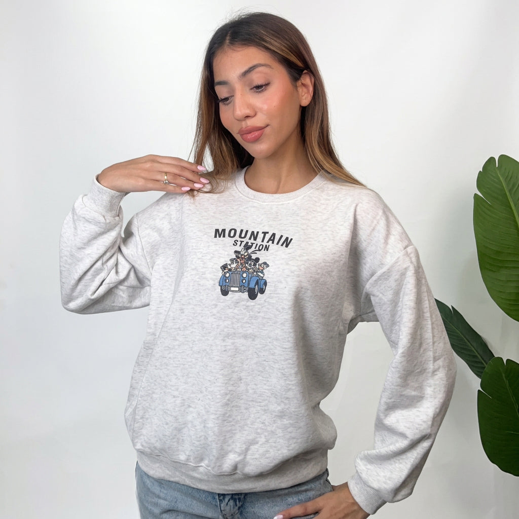 Woman in a light grey heather sweatshirt with a Mountain Station vintage car chest print