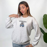 Woman in a light grey heather sweatshirt with a Mountain Station vintage car chest print