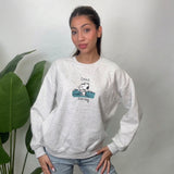 Woman in a light grey heather sweatshirt with a puppy scout chest graphic and light jeans