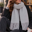 Light grey blanket scarf wrapped at the neck with soft twisted tassel ends