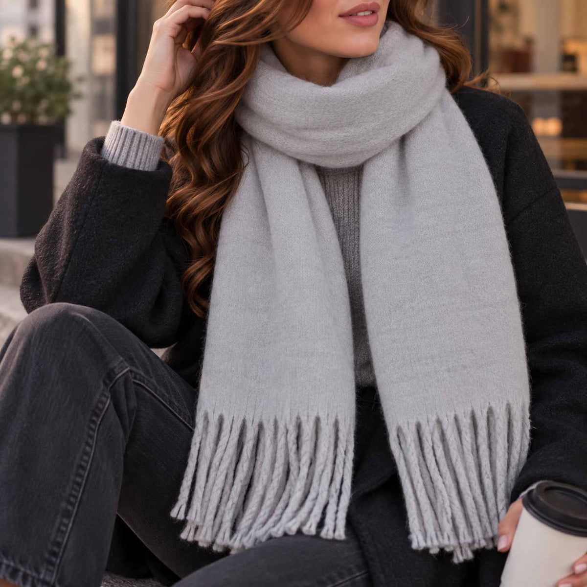 Light grey blanket scarf wrapped at the neck with soft twisted tassel ends