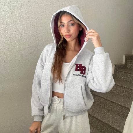 Light grey varsity patch zip hoodie worn with the hood up showing the burgundy hood lining