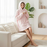 Person wearing a pink hooded robe sitting on a couch in a bright living room.